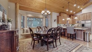 A spacious kitchen with wooden cabinets, a central island, and a dining area with a round table and chairs. - Stunning Large Custom Family Home with Fireplace, Hot tub, Yard, & Views! (South Lake Tahoe)