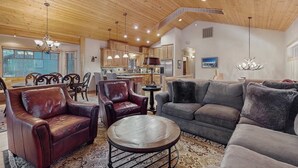 A spacious living area with leather armchairs, a grey sofa, a round coffee table, and a wooden ceiling. - Stunning Large Custom Family Home with Fireplace, Hot tub, Yard, & Views! (South Lake Tahoe)