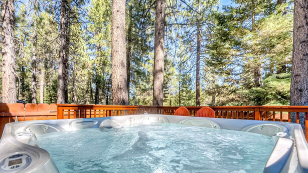 A hot tub surrounded by tall trees, with a wooden deck and orange chairs. - Dog Friendly Cabin with Hot Tub & Fireplace near Camp Richardson (South Lake Tahoe)