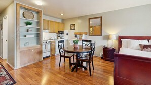 A compact living space with a dining area, kitchenette, and a bed.