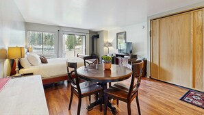 A room with a bed, a round dining table with chairs, a TV, and a wardrobe.