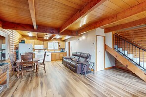 Ein Blockhaus-Innenraum mit Essbereich, einer Couch, einer Treppe und einer Küche.