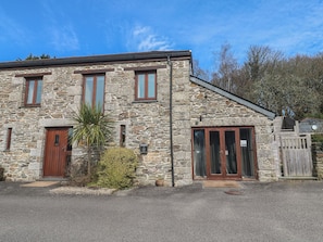 A stone building with a wooden door, a window, and a mailbox. - Ash Barn (Falmouth)