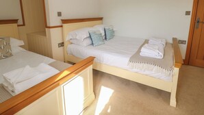 Ein Hotelzimmer mit zwei Betten, einem Holzkopfstück, einem Spiegel und einer Tür.