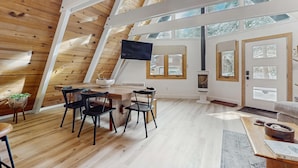 A modern interior with a wooden ceiling, a dining area with a table and chairs, and large windows allowing natural light. - Beautiful A-frame home with deck, streaming, and dog friendly - near skiing (South Lake Tahoe)