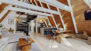 A loft-style interior with a kitchen, dining area, and living space, featuring exposed wooden beams and a spiral staircase. - Beautiful A-frame home with deck, streaming, and dog friendly - near skiing (South Lake Tahoe)