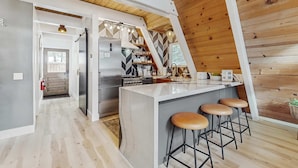 A modern kitchen with a central island, bar stools, and a view of the outdoors. - Beautiful A-frame home with deck, streaming, and dog friendly - near skiing (South Lake Tahoe)