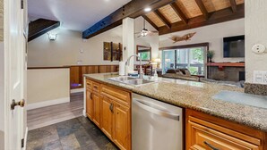 Una cocina con armarios de madera, encimeras de granito y lavavajillas.