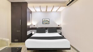 A modern hotel room with a bed, a wardrobe, a desk, and a wall-mounted air conditioner.