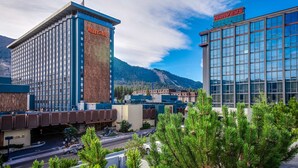 A hotel with a prominent Harveys sign, a modern glass building, and a mountainous backdrop. - Bright townhome with lazy days on the beach and bountiful relaxing amenities (South Lake Tahoe)