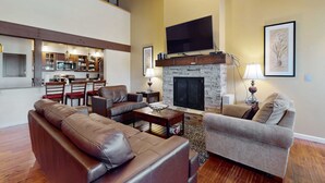 A living room with a fireplace, a television, and a dining area with chairs and a table. - Bright townhome with lazy days on the beach and bountiful relaxing amenities (South Lake Tahoe)