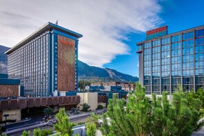 Un hotel con un llamativo letrero de Harveys, un moderno edificio de cristal y un paisaje montañoso de fondo.