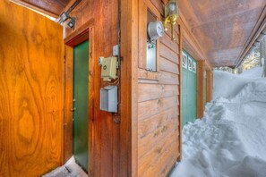 A wooden cabin with a green door, a window with a light fixture, and a snow-covered exterior. - Charming Tahoe Donner home with 2 fireplaces & washer&dryer (Truckee)