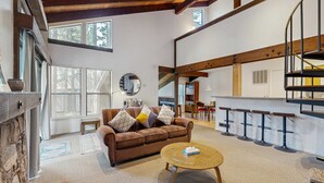 A spacious living area with a brown sofa, a round coffee table, and a spiral staircase.