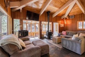 A cozy cabin interior with a fireplace, wooden walls, and a stone floor. - Charming home with private hot tub (Carnelian Bay)