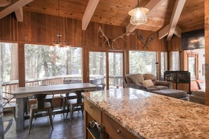 A wooden interior with a dining table, chairs, a sofa, and a TV. - Charming home with private hot tub (Carnelian Bay)