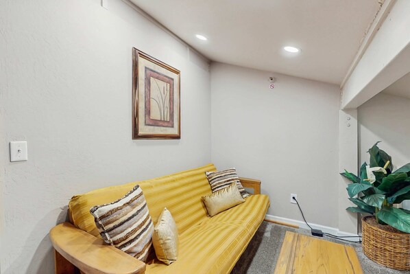 A room with a sofa, pillows, a framed picture, a plant, and a power outlet. - Updated Condo with Lake Views, Heated Floors, Soaking Tub (Stateline)
