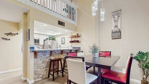 A dining area with a stone island, wooden chairs, and a modern kitchen in the background.