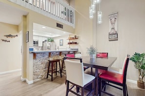 A dining area with a stone island, wooden chairs, and a modern kitchen in the background. - Updated Condo with Lake Views, Heated Floors, Soaking Tub (Stateline)