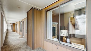 A hotel corridor with wooden paneling, a carpeted floor, and a window with a 'Welcome' sign.