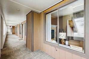 A hotel corridor with wooden paneling, a carpeted floor, and a window with a 'Welcome' sign. - Updated Condo with Lake Views, Heated Floors, Soaking Tub (Stateline)