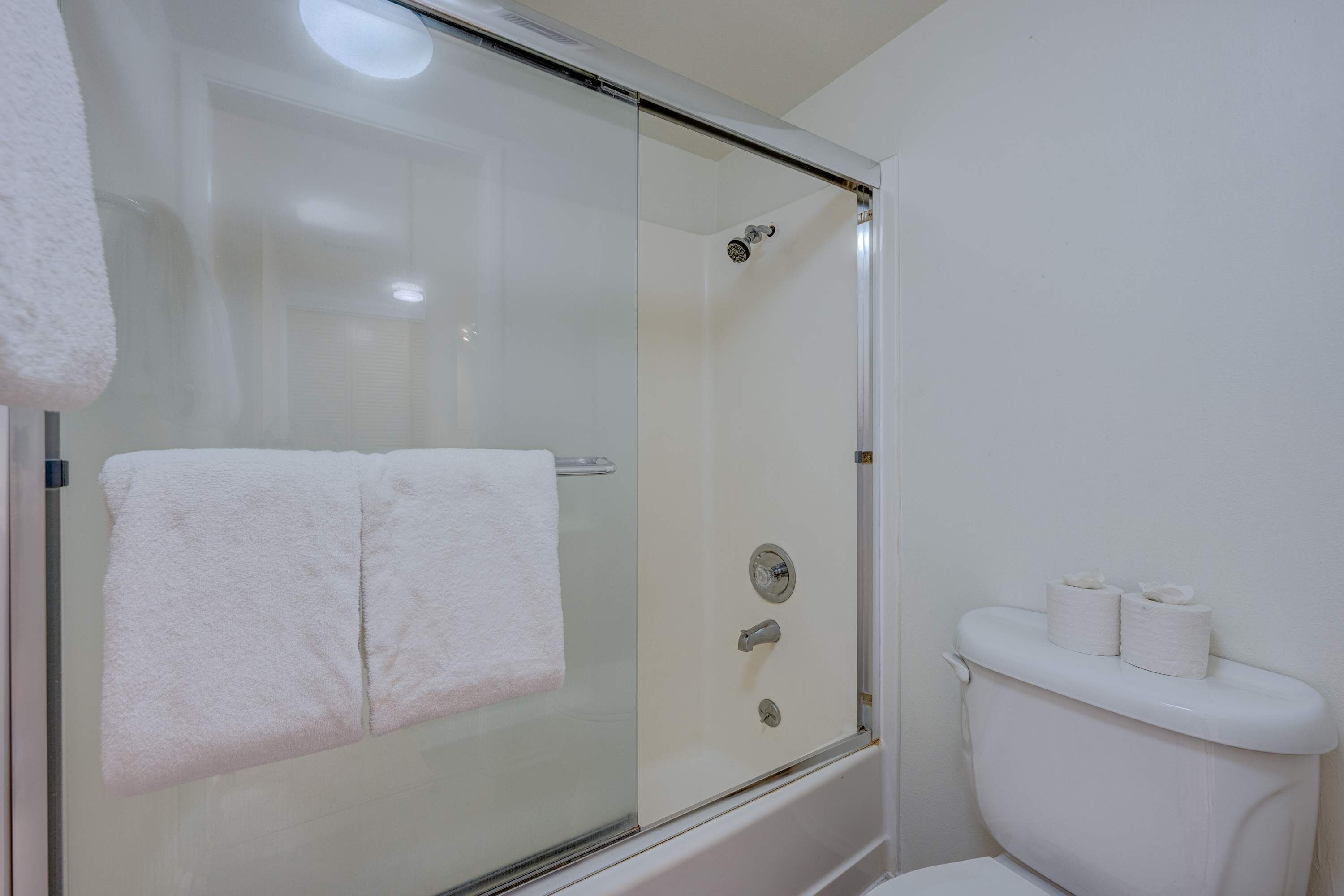 Un baño con ducha de vidrio, inodoro blanco y una toalla colgada en la pared.