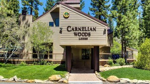 A building labeled 'Carnelian Woods' with a prominent entrance, surrounded by a well-maintained lawn and trees. - Charming Condo with Shared Hot Tub, Pool, Resort Amenities - Close to Ski & Beach (Carnelian Bay)