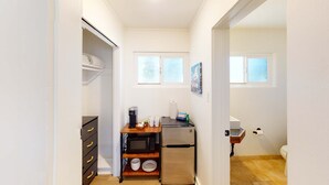 A compact kitchen with a refrigerator, microwave, and a small wooden table.