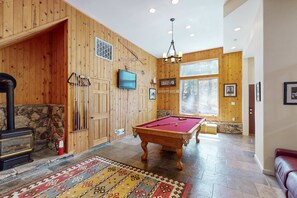 Un interior de madera con mesa de billar, chimenea y pared de piedra.