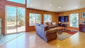 A spacious living room with a large sofa, a television, and a wooden floor. - Stateline Chalet -  5BR, Panoramic Mountain Views, Dipping Pool & Dry Sauna (Stateline)