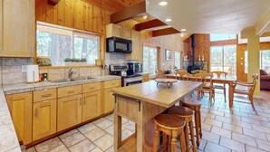 A kitchen with wooden cabinets, a central island with stools, a microwave, and a coffee maker. - Stateline Chalet -  5BR, Panoramic Mountain Views, Dipping Pool & Dry Sauna (Stateline)