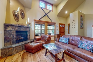 A living room with a stone fireplace, leather furniture, and a wooden floor. - Quiet Cottage with Deck & Firepit - Near Skiing, Golf, Park & Water Sports (Truckee)