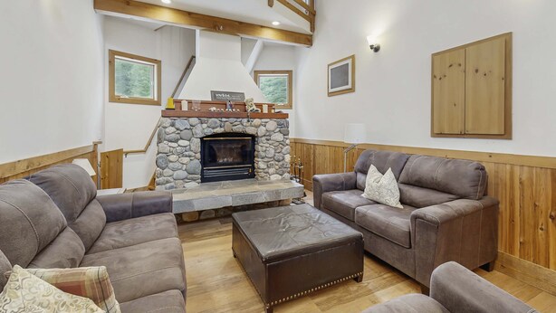 Ein Wohnzimmer mit Kamin aus Stein, Holzboden und zwei Ledersofas.