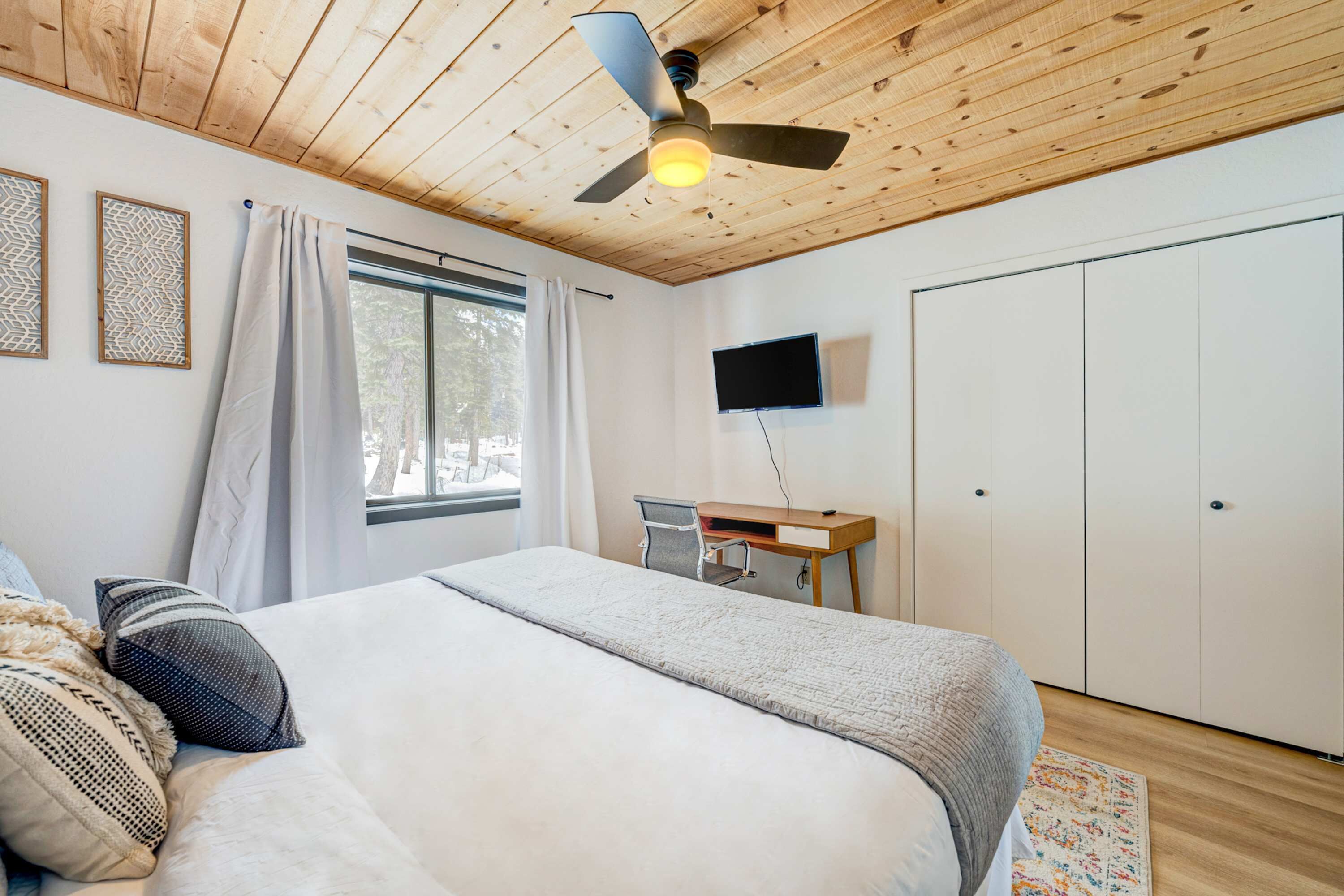 Ein Schlafzimmer mit einem Bett, einem Schreibtisch, einem Stuhl, einem Fernseher und einem Kleiderschrank.
