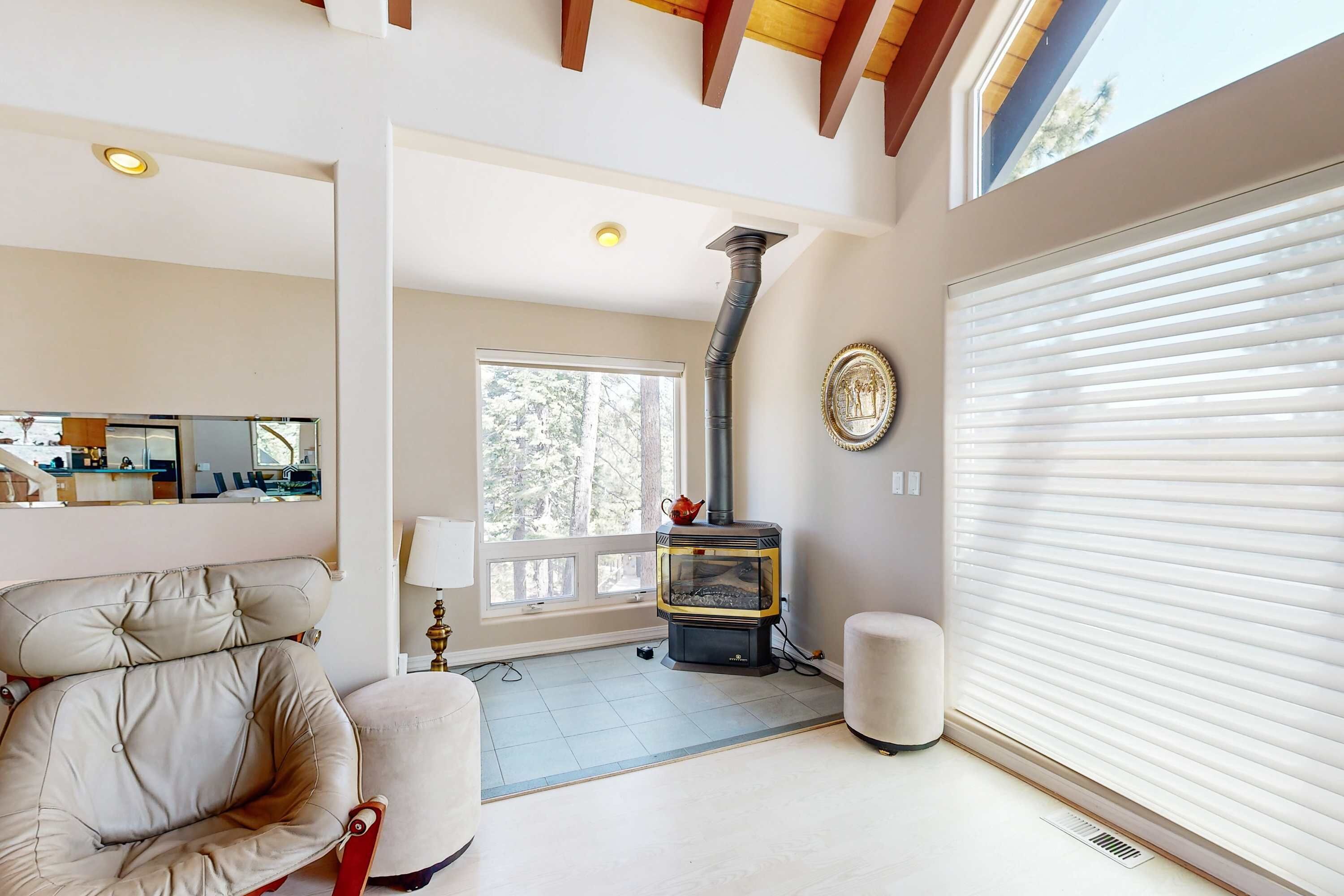 A room with a fireplace, a large window, a chair, and a closed sliding door.