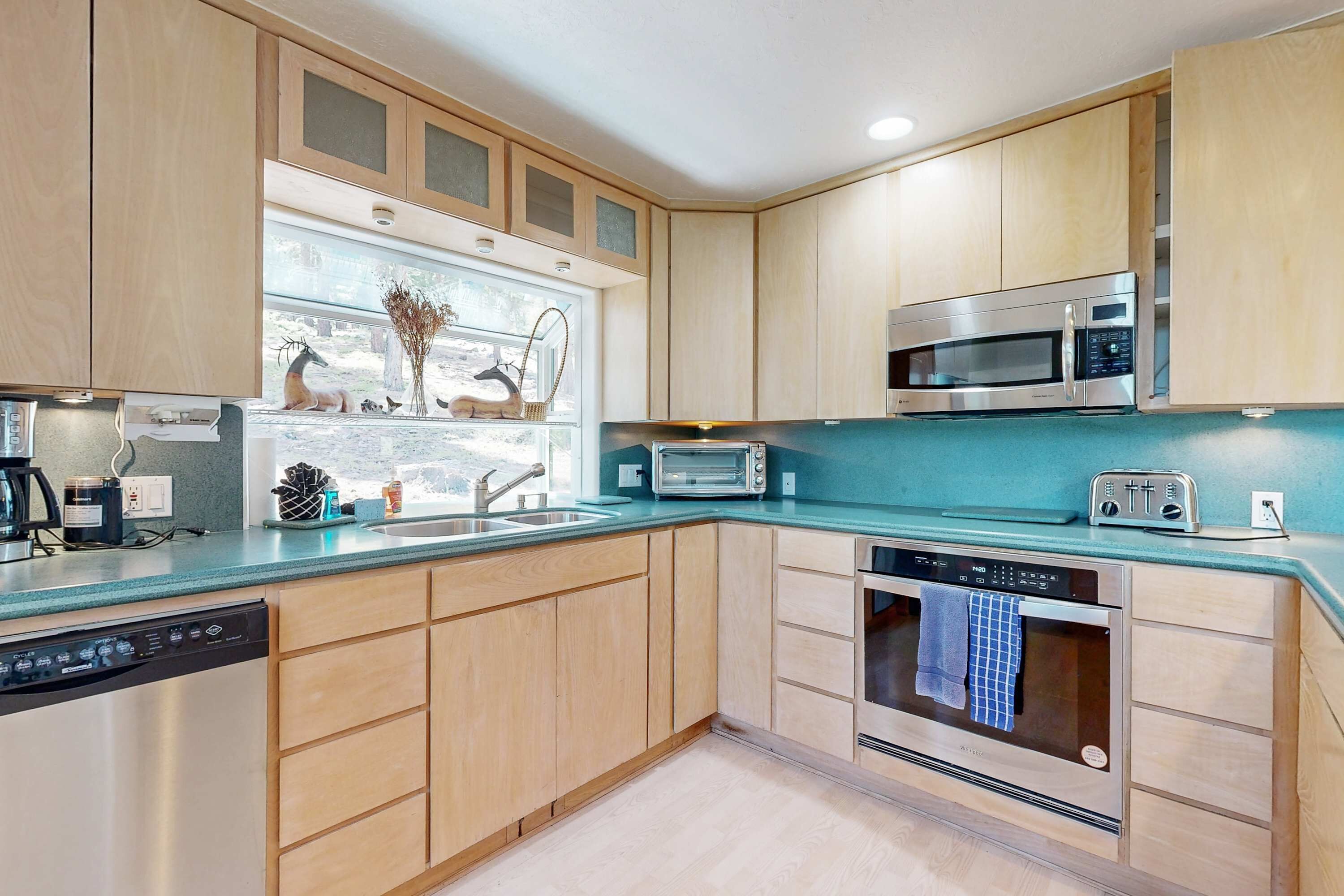 A modern kitchen with wooden cabinets, a stainless steel microwave, a toaster, and a dishwasher.