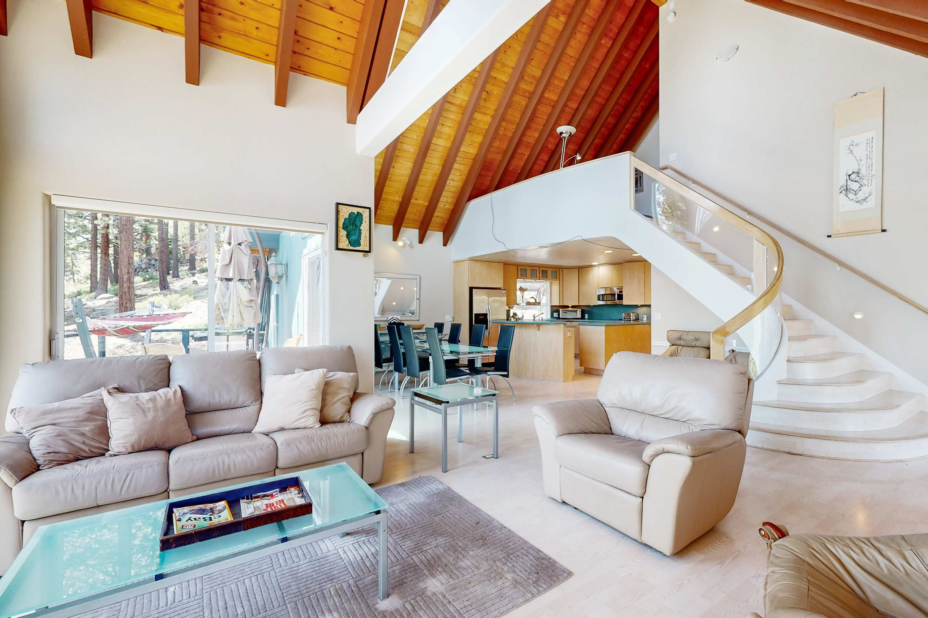 Een ruime woonkamer met een hoge plafond, een trap en uitzicht op de omgeving.