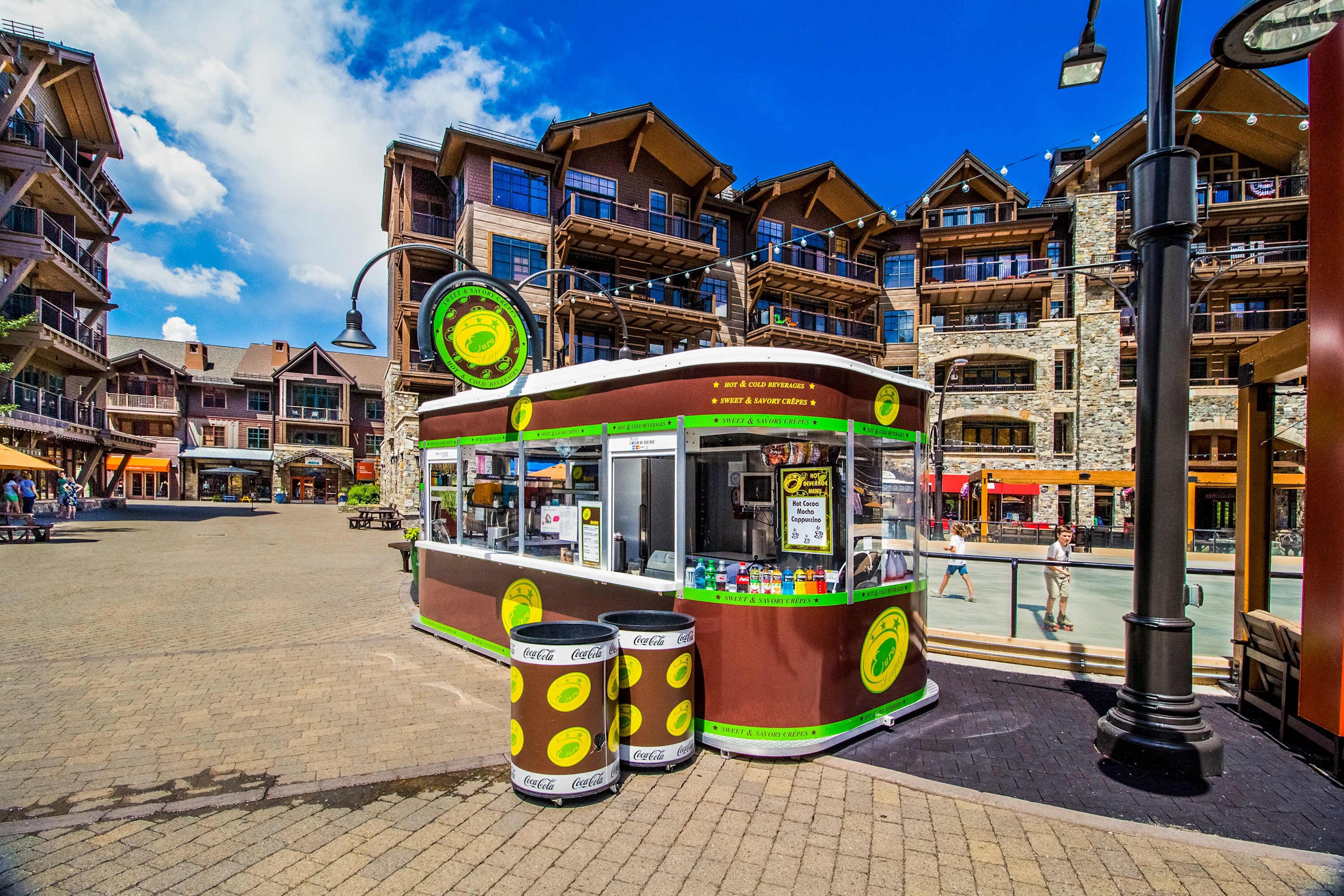 Un chariot de vente de nourriture, aménagé comme un tramway, avec des canettes de Coca-Cola, une enseigne indiquant les boissons chaudes et froides, et un panneau affichant le menu.