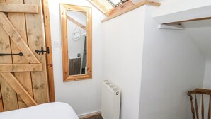 Ein Schlafzimmer mit Holztür, Spiegel, Heizkörper, Bett und Stuhl.