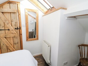 Ein Schlafzimmer mit Holztür, Spiegel, Heizkörper, Bett und Stuhl.