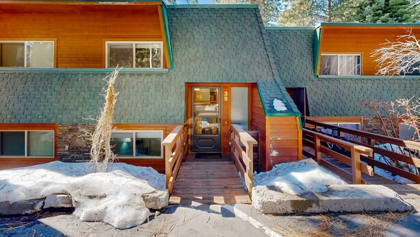 A two-story log cabin with a wooden deck and a stone wall. - Forest-view condo with wood fireplace & walkable locale - dog-friendly (Incline Village)