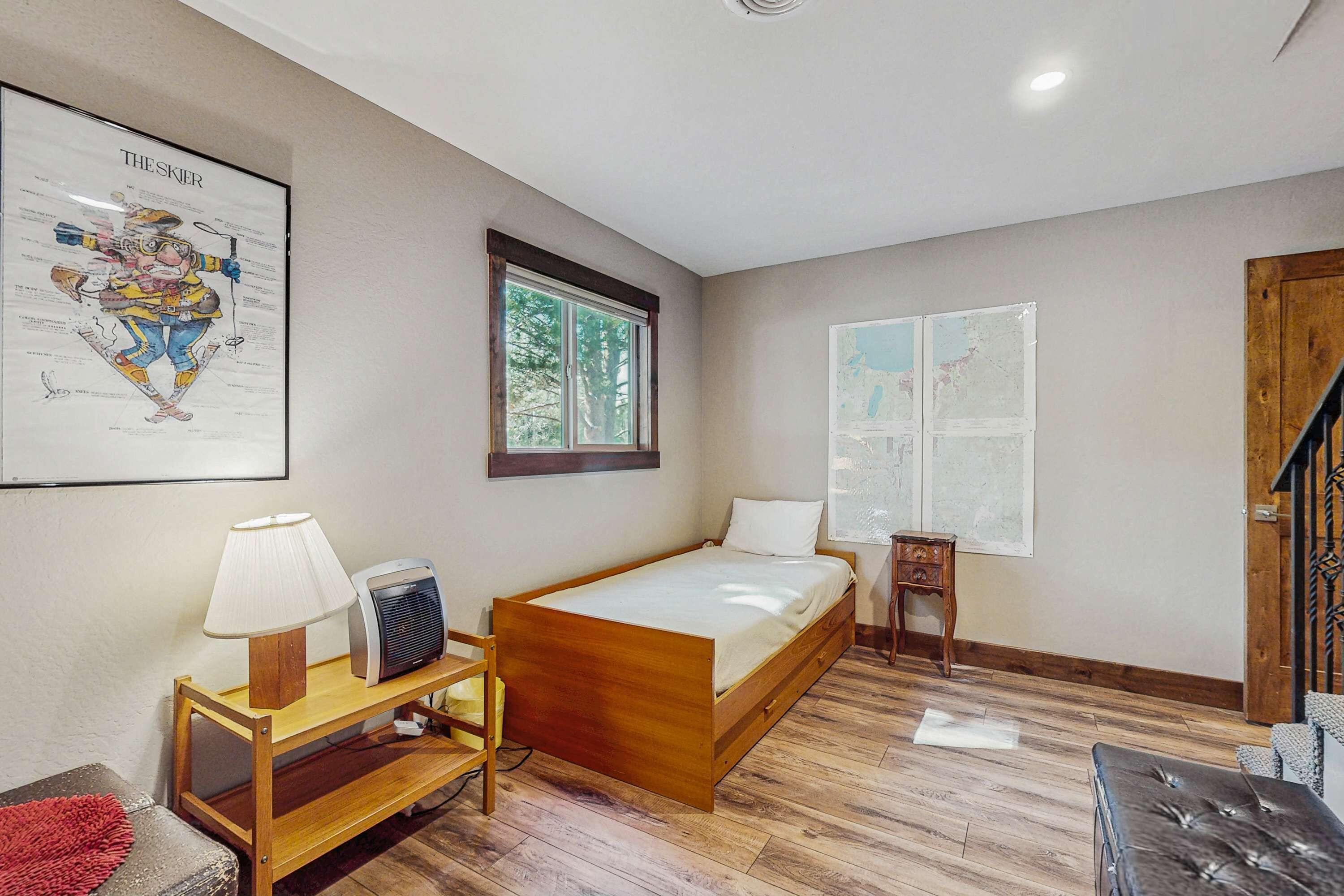 Une chambre à coucher avec un lit en bois, un bureau avec une lampe, une chaise et une carte accrochée au mur.