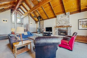 A spacious living room with a stone fireplace, a television, and leather furniture. - Lake Tahoe Golf Course Home: Views, Skiing, Hiking & Biking! (South Lake Tahoe)