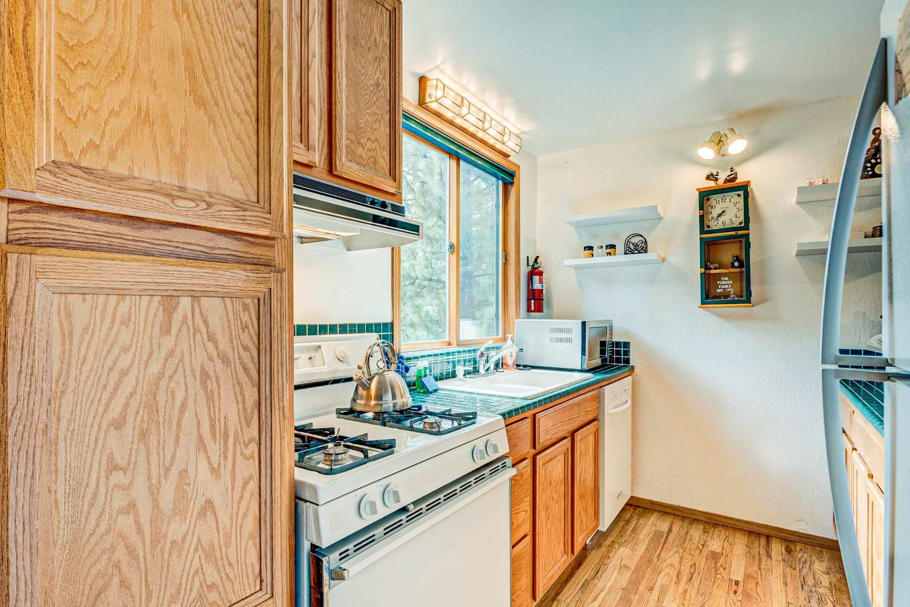 Une cuisine avec des meubles de rangement en bois, une cuisinière, un four à micro-ondes et un évier.