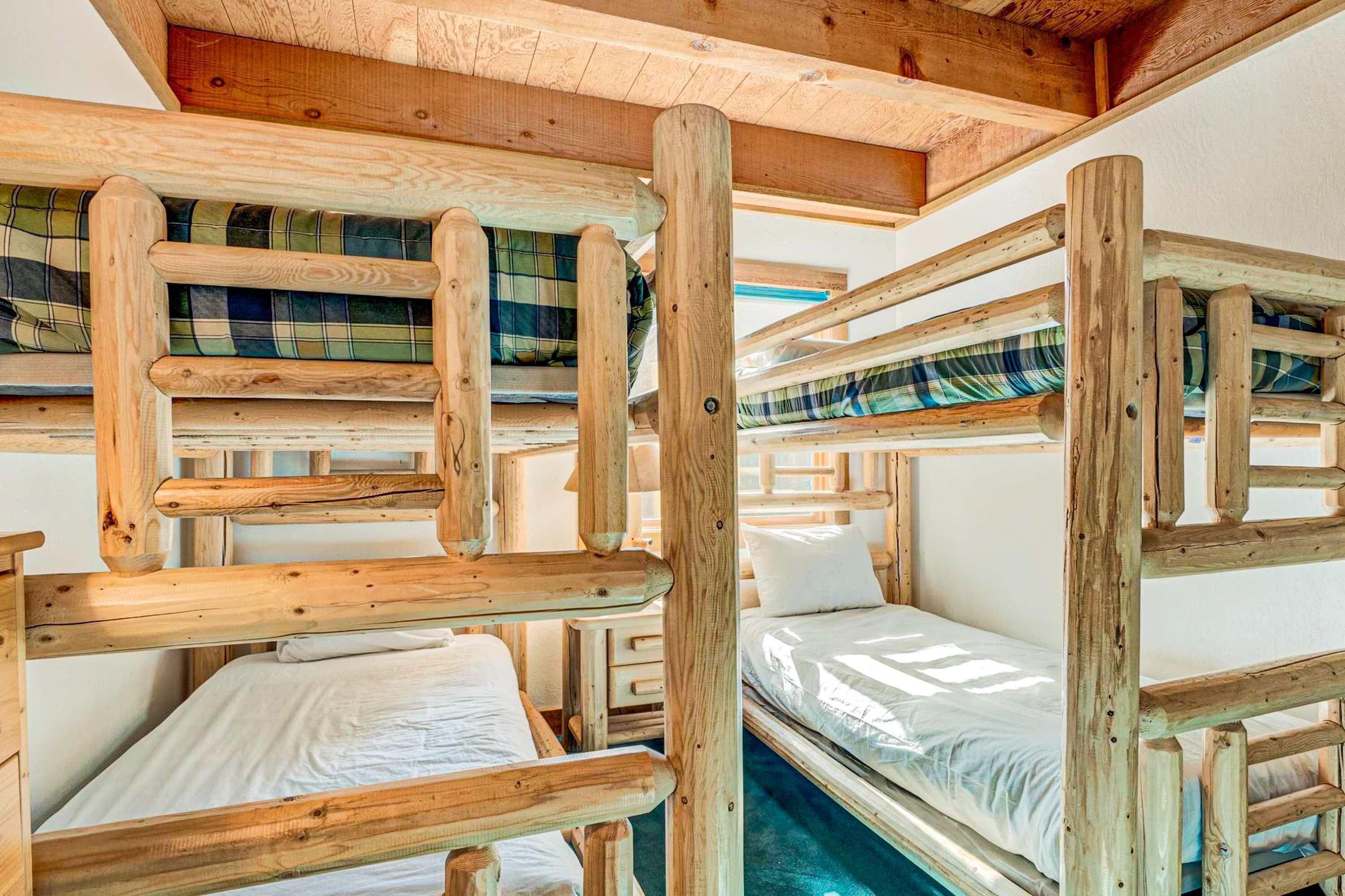 Dormitorio con literas de madera y ropa de cama escocesa.