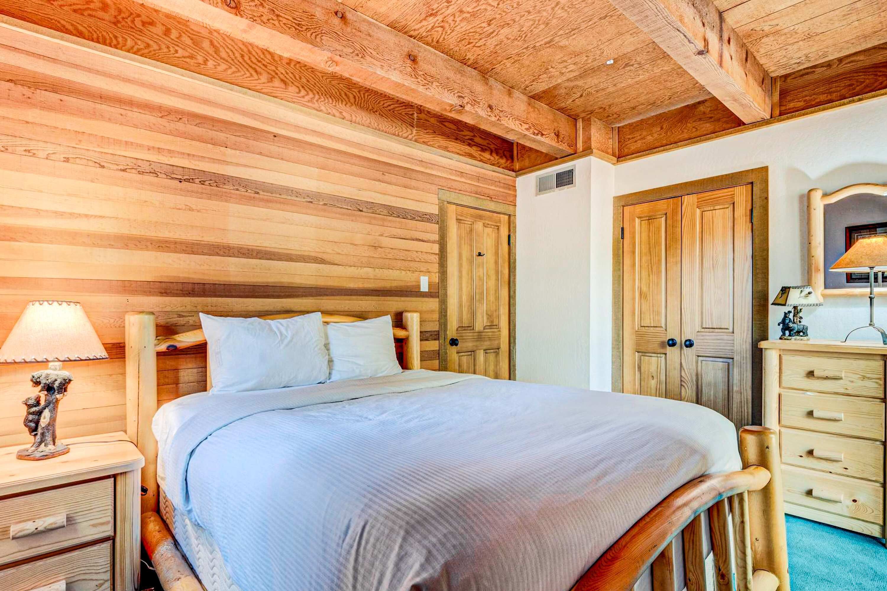 A wooden-paneled bedroom with a bed, nightstand, dresser, and wardrobe.