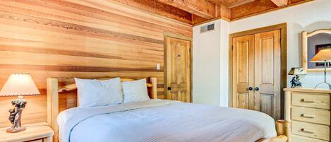 A wooden-paneled bedroom with a bed, nightstand, dresser, and wardrobe.