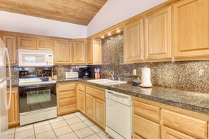 A modern kitchen with wooden cabinets, a granite countertop, a built-in oven, a dishwasher, and a microwave. - Lakefront getaway with Private beach access & balcony, sleeps 6 (Zephyr Cove)