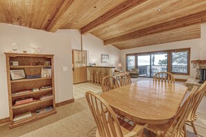 A spacious dining area with a wooden table and chairs, a bookshelf with books, and a kitchen in the background. - Lakefront getaway with Private beach access & balcony, sleeps 6 (Zephyr Cove)