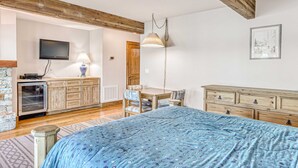 Een slaapkamer met een bed, een houten dressoir, een televisie en een eethoek.